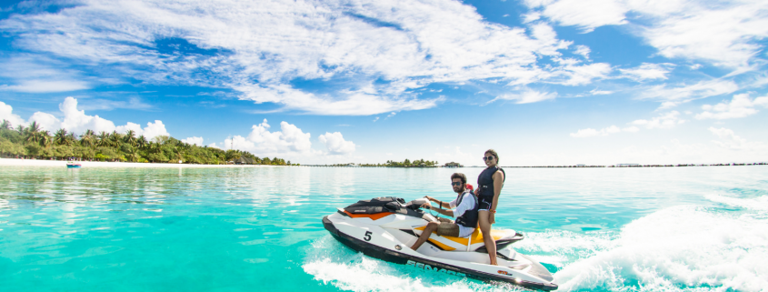 Humans on jet ski in the water near an island